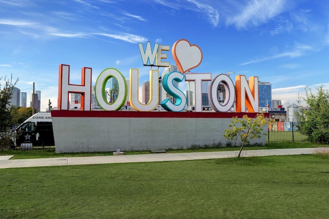 community sign with a yard, a view of city, and fence