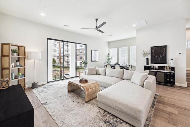 living room with baseboards, light wood-type flooring, recessed lighting, a ceiling fan, and visible vents