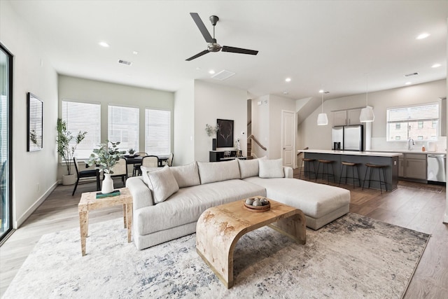 living area with light wood-style floors, ceiling fan, visible vents, and recessed lighting