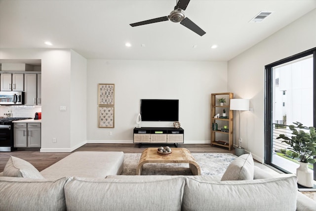 living room with wood finished floors, a ceiling fan, visible vents, and recessed lighting