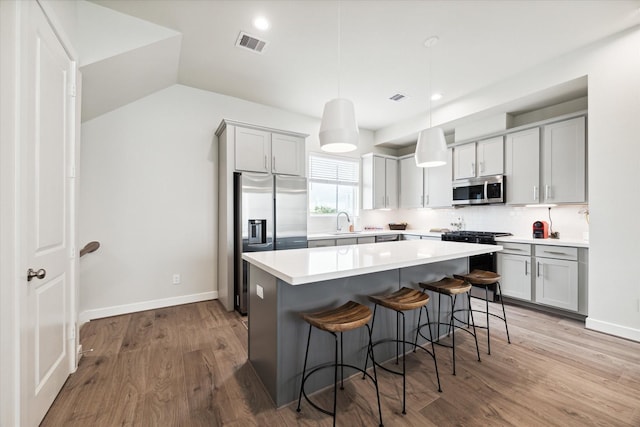 kitchen with light wood-style flooring, a sink, a kitchen breakfast bar, and stainless steel appliances