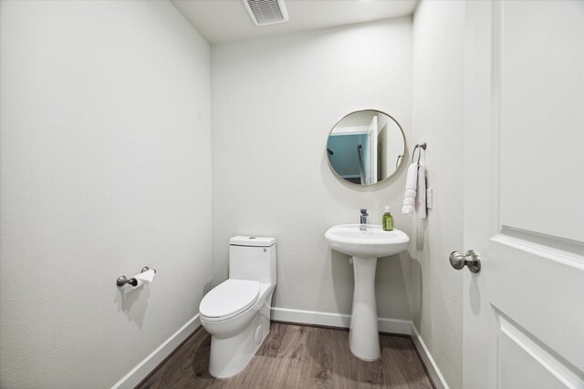 bathroom with visible vents, baseboards, toilet, and wood finished floors