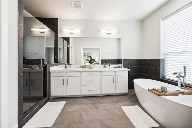 bathroom with a shower stall, visible vents, a sink, a freestanding bath, and double vanity