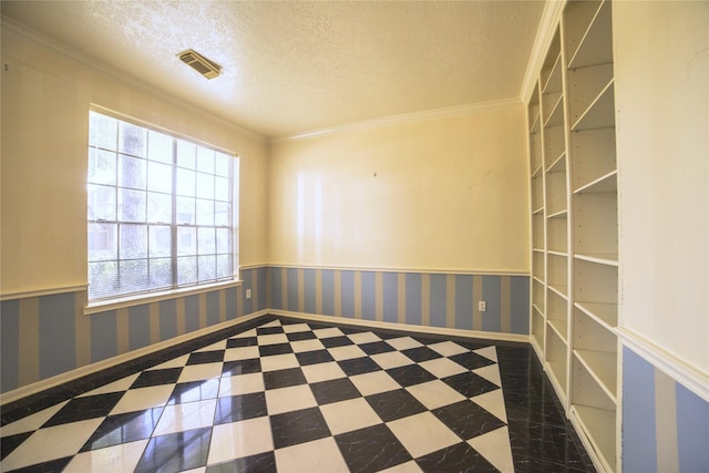 empty room with wainscoting, ornamental molding, a textured ceiling, and visible vents