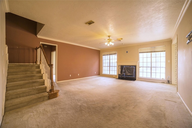 unfurnished living room featuring a high end fireplace, visible vents, carpet floors, crown molding, and a textured ceiling