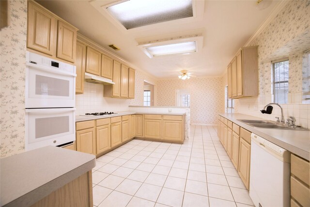 kitchen featuring under cabinet range hood, wallpapered walls, a sink, and white appliances