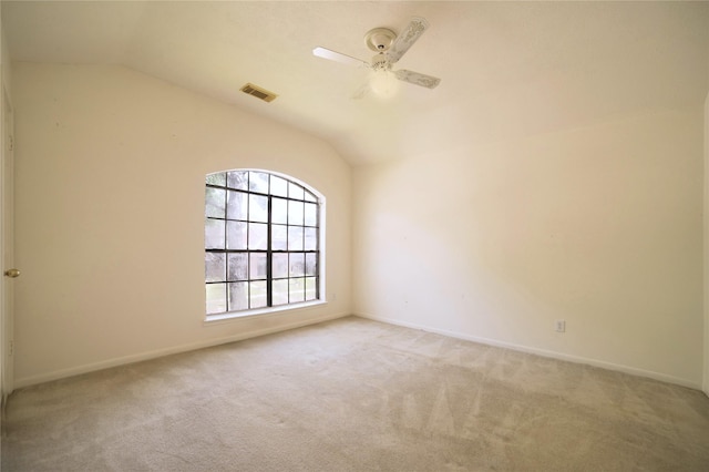 spare room with ceiling fan, vaulted ceiling, visible vents, and carpet flooring