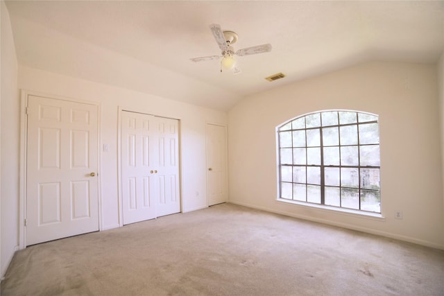 unfurnished bedroom featuring vaulted ceiling, visible vents, carpet, a closet, and ceiling fan