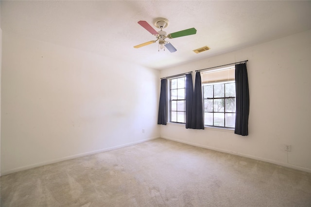 carpeted spare room featuring baseboards, a ceiling fan, and visible vents