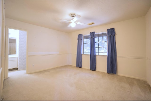 carpeted spare room featuring ceiling fan, baseboards, and visible vents