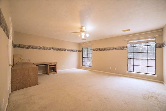 spare room featuring plenty of natural light, visible vents, carpet flooring, and ceiling fan