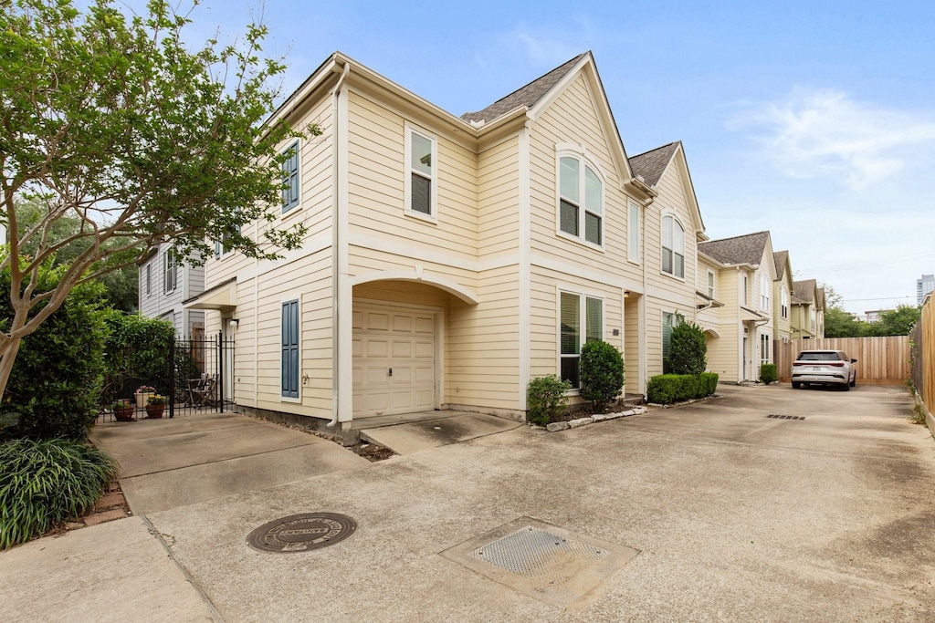 view of front of house with concrete driveway, a garage, and fence
