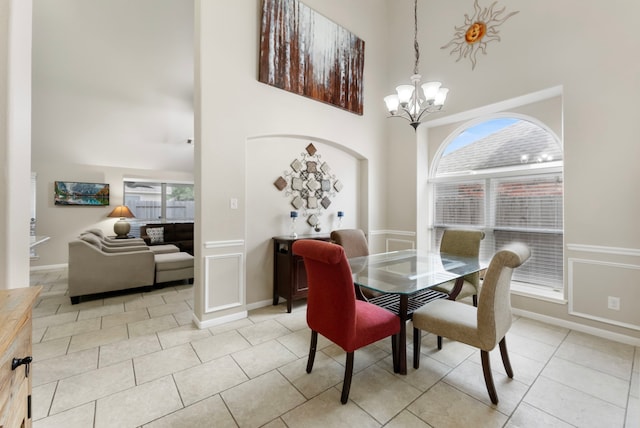 8322 Calico Canyon Dr, Tomball, TX 77375 - dining room featuring a towering ceiling, a chandelier, light tile patterned flooring, and baseboards