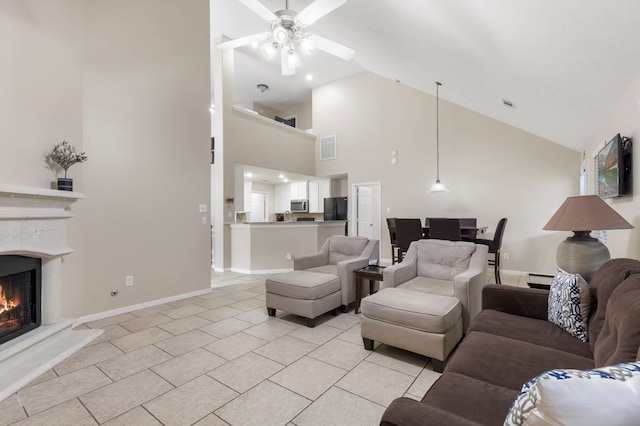 8322 Calico Canyon Dr, Tomball, TX 77375 - living room featuring a ceiling fan, light tile patterned flooring, high vaulted ceiling, a warm lit fireplace, and baseboards