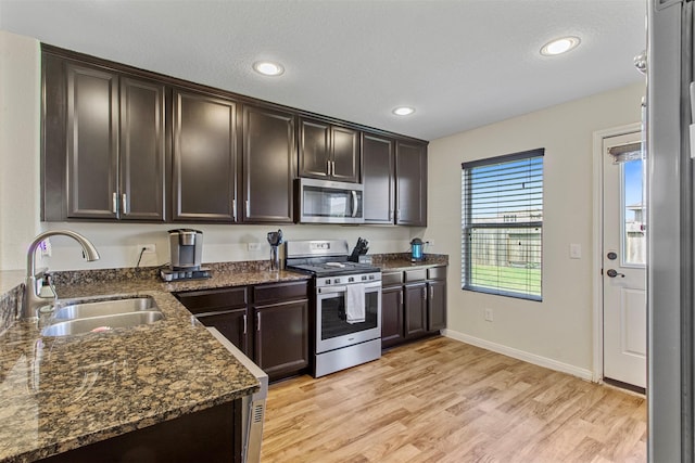6803 Cortenridge Ln, Houston, TX 77048 - kitchen with stainless steel appliances, a sink, dark brown cabinets, light wood-style floors, and dark stone counters