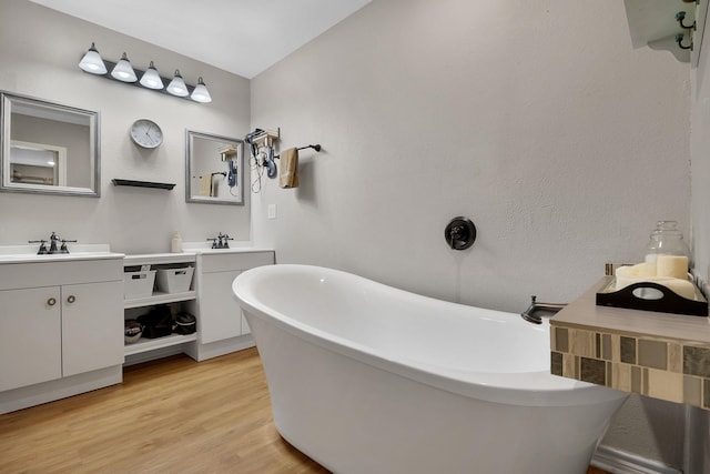 310 Hidden Oaks Dr, Point Blank, TX 77364 - full bathroom featuring two vanities, a freestanding tub, wood finished floors, and a sink