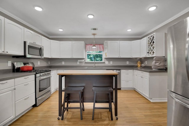 310 Hidden Oaks Dr, Point Blank, TX 77364 - kitchen with white cabinets, ornamental molding, light wood-type flooring, and appliances with stainless steel finishes