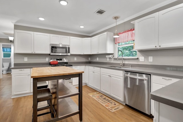 310 Hidden Oaks Dr, Point Blank, TX 77364 - kitchen featuring a sink, appliances with stainless steel finishes, white cabinetry, ornamental molding, and visible vents
