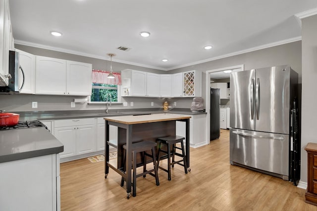 310 Hidden Oaks Dr, Point Blank, TX 77364 - kitchen featuring a sink, stainless steel appliances, white cabinetry, ornamental molding, and visible vents
