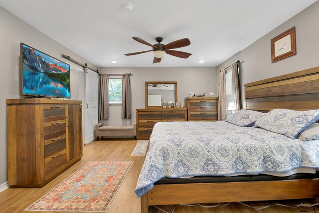 310 Hidden Oaks Dr, Point Blank, TX 77364 - bedroom featuring a barn door, baseboards, a ceiling fan, and light wood-type flooring