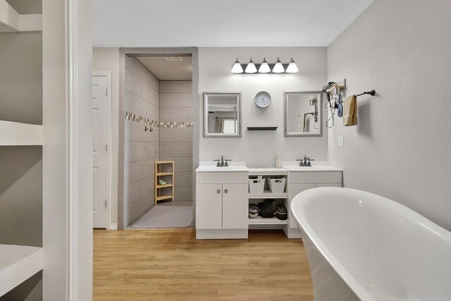 310 Hidden Oaks Dr, Point Blank, TX 77364 - bathroom featuring wood finished floors, a sink, walk in shower, a freestanding bath, and two vanities
