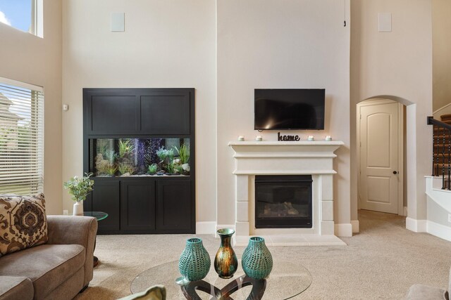 3225 Summer Tanager Ln, Manvel, TX 77578 - carpeted living room featuring a towering ceiling, a fireplace with flush hearth, arched walkways, healthy amount of natural light, and baseboards