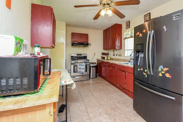 1905 Tennessee St, Baytown, TX 77520 - kitchen with light tile patterned floors, light countertops, a ceiling fan, under cabinet range hood, and stainless steel appliances