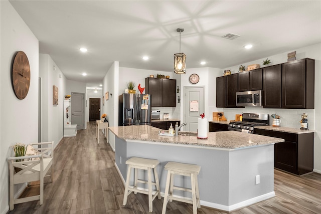 1143 Grand Junction Dr, Tomball, TX 77375 - kitchen with stainless steel appliances, dark brown cabinets, visible vents, a sink, and light wood-style flooring