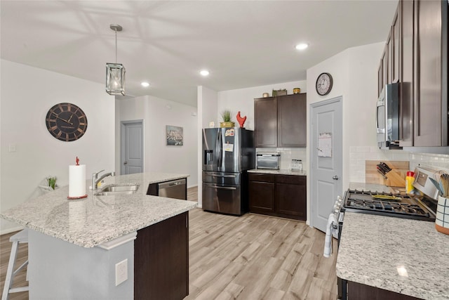 1143 Grand Junction Dr, Tomball, TX 77375 - kitchen with stainless steel appliances, backsplash, dark brown cabinets, a sink, and light wood-style flooring