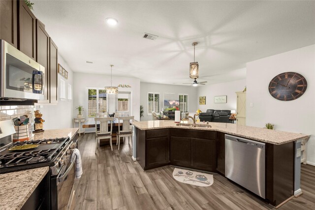 1143 Grand Junction Dr, Tomball, TX 77375 - kitchen with dark brown cabinets, wood finished floors, appliances with stainless steel finishes, open floor plan, and ceiling fan