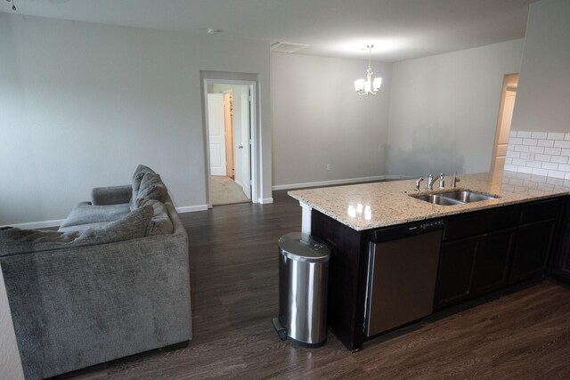 kitchen with stainless steel dishwasher, light stone counters, a sink, a notable chandelier, and dark wood-style floors