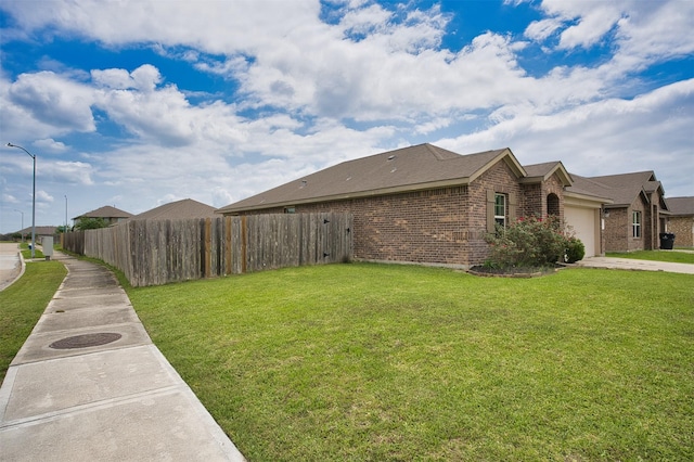 view of property exterior featuring a garage, brick siding, fence, and a lawn