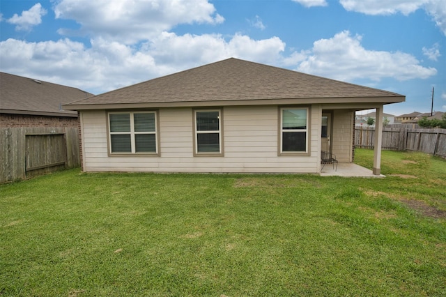 back of property featuring a yard, a patio, a fenced backyard, and a shingled roof