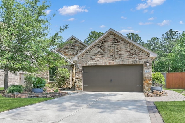 114 Winecup Cir, Montgomery, TX 77316 - view of front of house featuring an attached garage, fence, stone siding, and driveway
