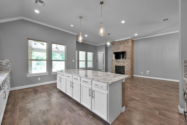 114 Winecup Cir, Montgomery, TX 77316 - kitchen with visible vents, a stone fireplace, dark wood finished floors, crown molding, and white cabinetry