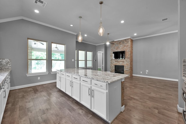 114 Winecup Cir, Montgomery, TX 77316 - kitchen with visible vents, a stone fireplace, dark wood finished floors, crown molding, and white cabinetry