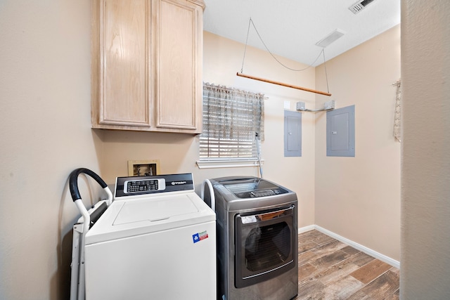 laundry area featuring electric panel, washer and clothes dryer, wood finished floors, and cabinet space