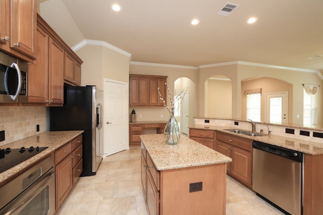 kitchen featuring visible vents, a sink, an island with sink, brown cabinets, and stainless steel appliances
