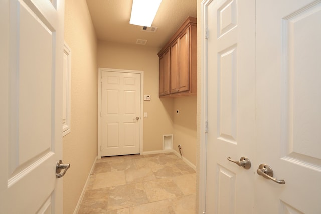 washroom with stone finish floor, visible vents, hookup for an electric dryer, baseboards, and cabinet space