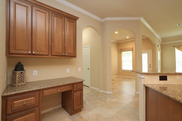 unfurnished office featuring arched walkways, ornamental molding, visible vents, built in study area, and baseboards