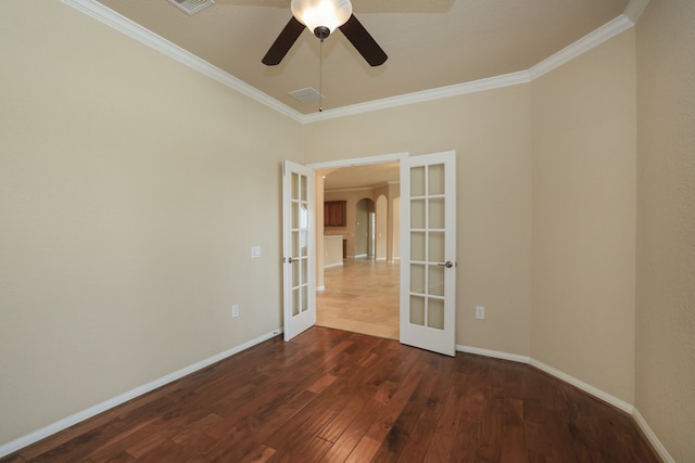 spare room featuring baseboards, arched walkways, ornamental molding, dark wood finished floors, and french doors