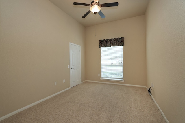 empty room featuring light colored carpet, ceiling fan, and baseboards