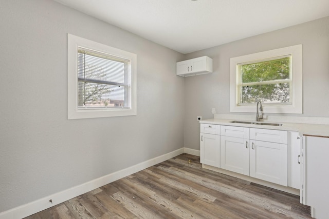 laundry room with baseboards, a sink, and light wood finished floors