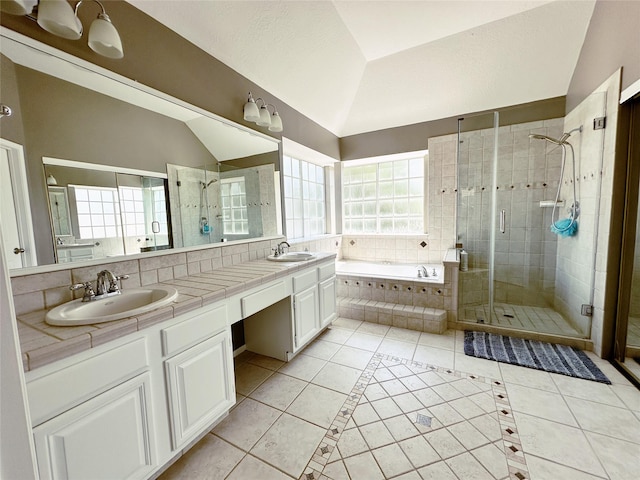 full bath with a garden tub, tile patterned flooring, vaulted ceiling, and a sink