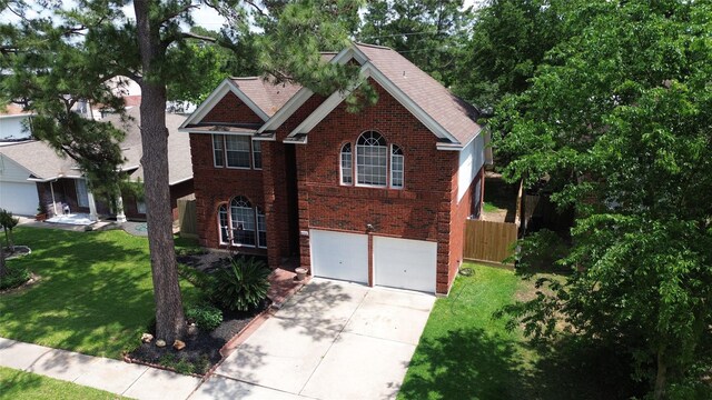 view of front of property with a front lawn, driveway, brick siding, an attached garage, and fence