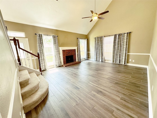 living area with wood finished floors, stairs, ceiling fan, baseboards, and high vaulted ceiling