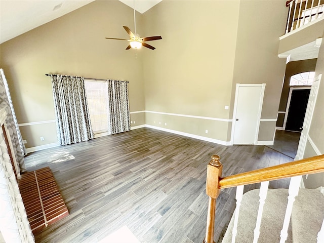 unfurnished living room with ceiling fan, baseboards, a fireplace, wood finished floors, and high vaulted ceiling