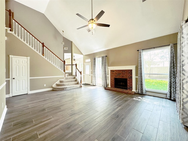 unfurnished living room with baseboards, wood finished floors, a ceiling fan, high vaulted ceiling, and stairs