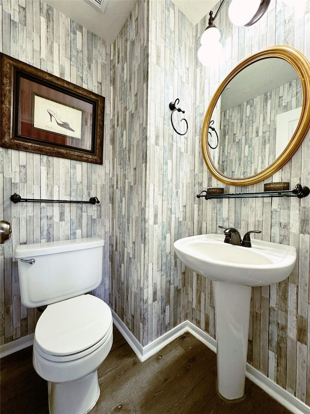 bathroom featuring toilet, wood finished floors, and baseboards