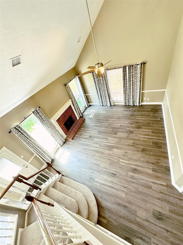 living room with wood finished floors, high vaulted ceiling, visible vents, and baseboards